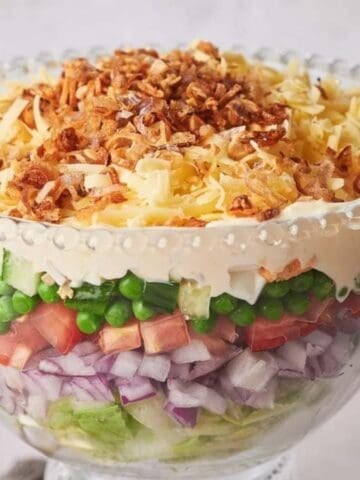 A glass container filled with 7 Layer Salad.