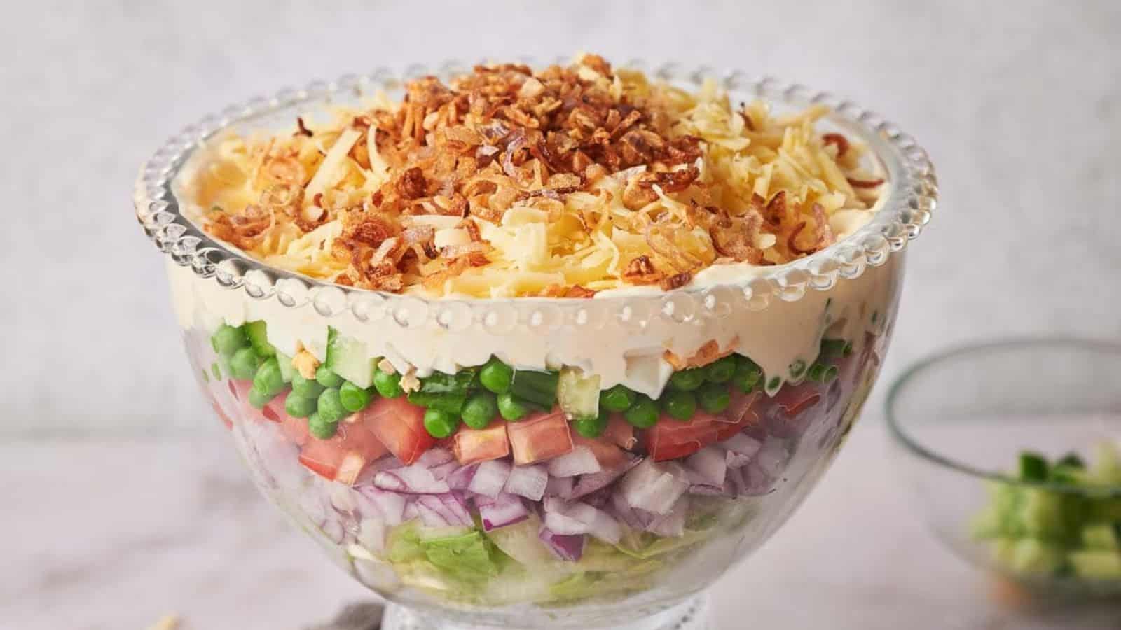 A glass container filled with 7 Layer Salad.