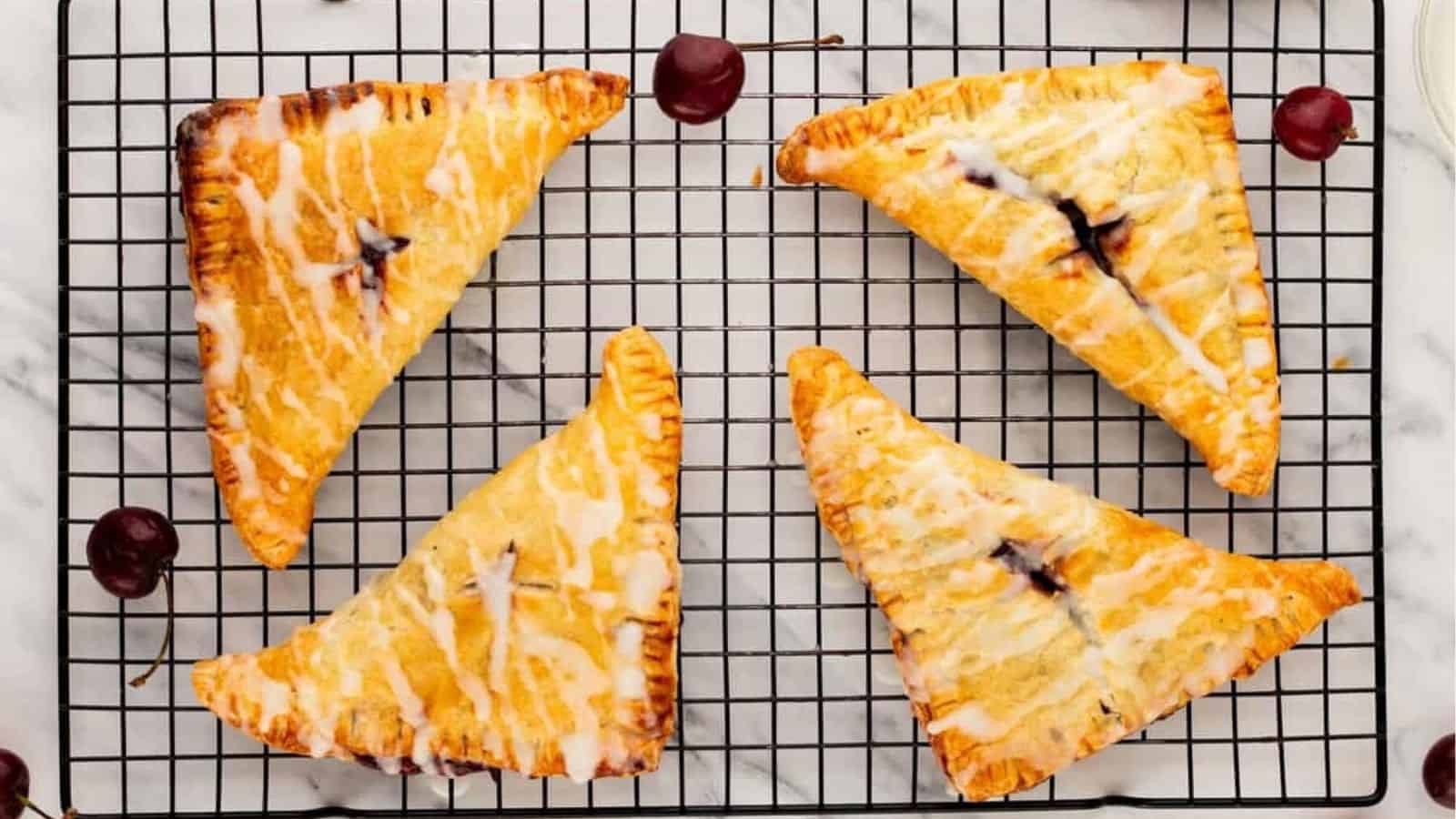 An overhead image of four cherry turnovers on a wire rack.