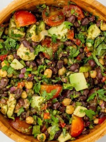 An overview of a bowl of dense bean salad surrounded by fresh ingredients.