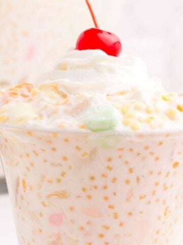 An image of Frog Eye Salad on a glass cup topped with cherry.