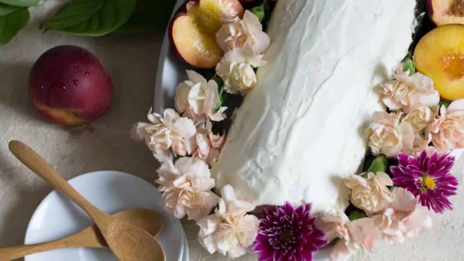 An overview of Peach Swiss Roll surrounded by fresh flowers and peaches.