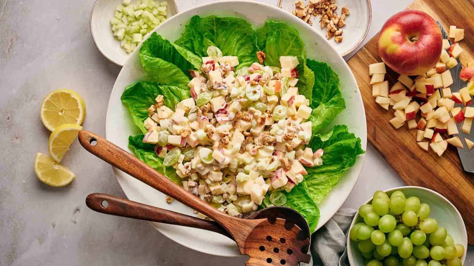 An overview of a plate of Waldorf Salad with wooden spoons, surrounded by fresh ingredients.