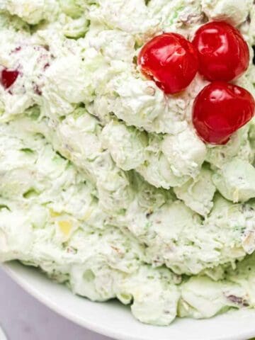 A close-up view of a bowl of Watergate Salad with cherries on top.