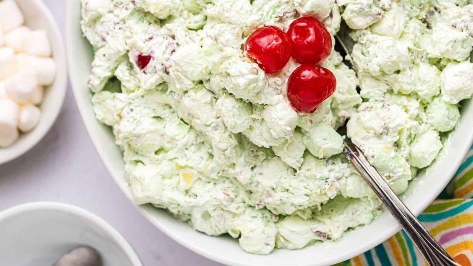 A close-up view of a bowl of Watergate Salad with cherries on top.