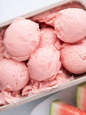 An overview of Watermelon Ice Cream scoops on a tray surrounded by fresh watermelon slices.