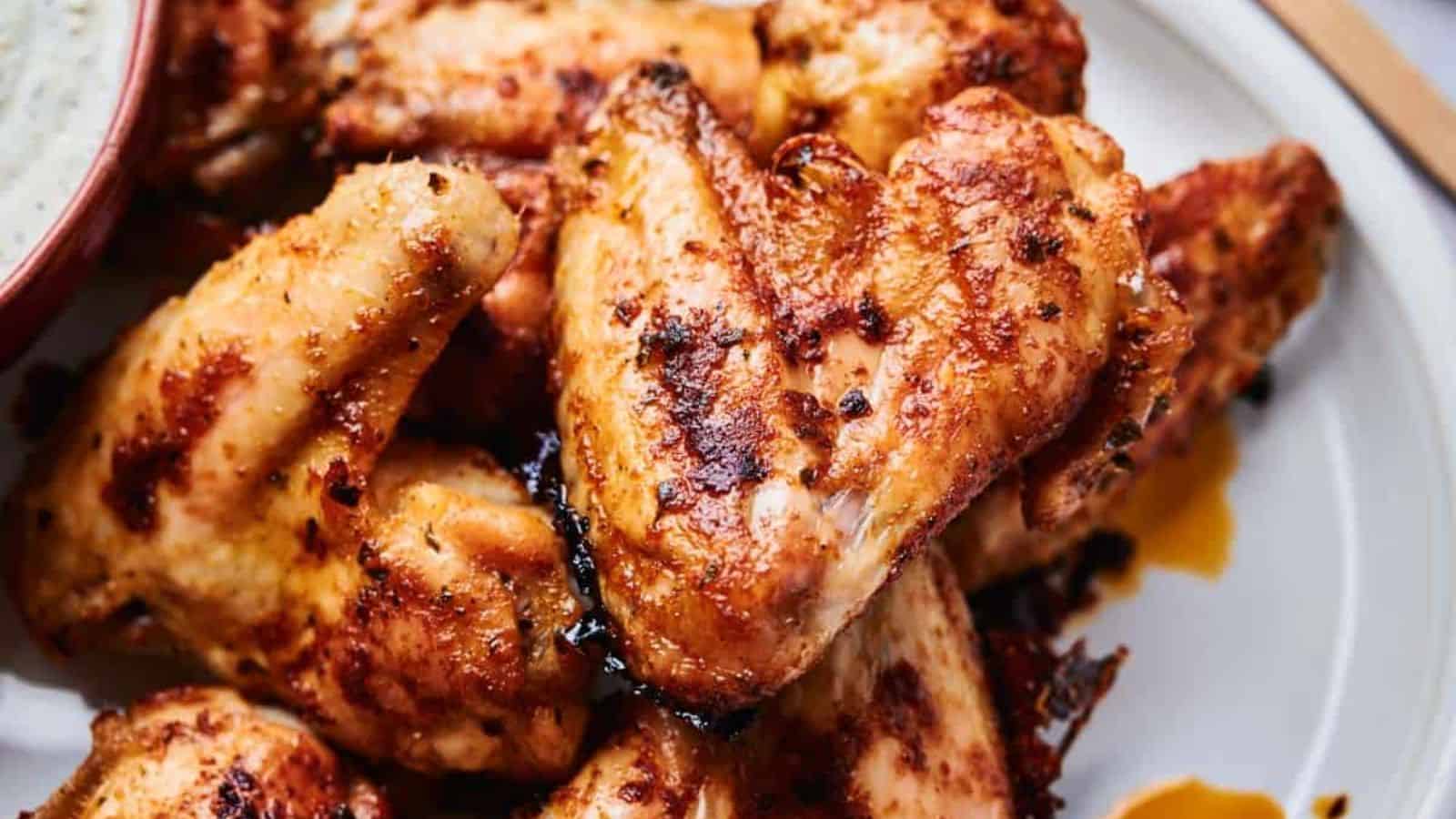 A stack of Wingstop Louisiana Rub Wings on a plate with a dip.