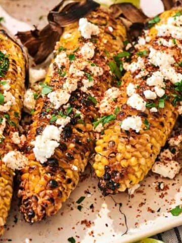 Four Grilled Corn on the Cob on a plate.