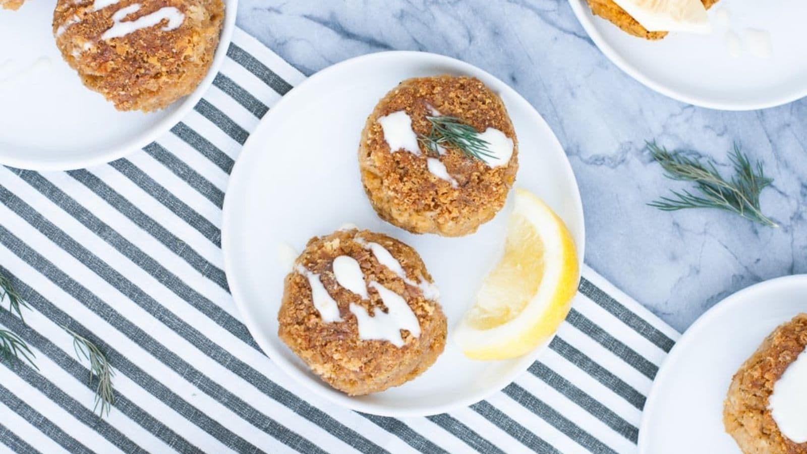 Two Tuna Cakes on a plate with a slice of lemon.
