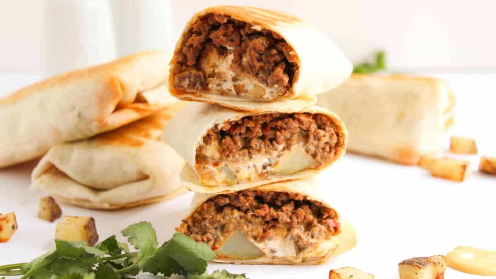 A stack of three Beef and Potato Burritos and more of them on the background.