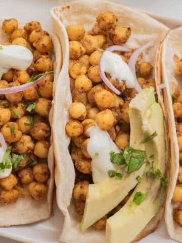 Overhead shot of three chickpea shawarma tacos on a white tray.