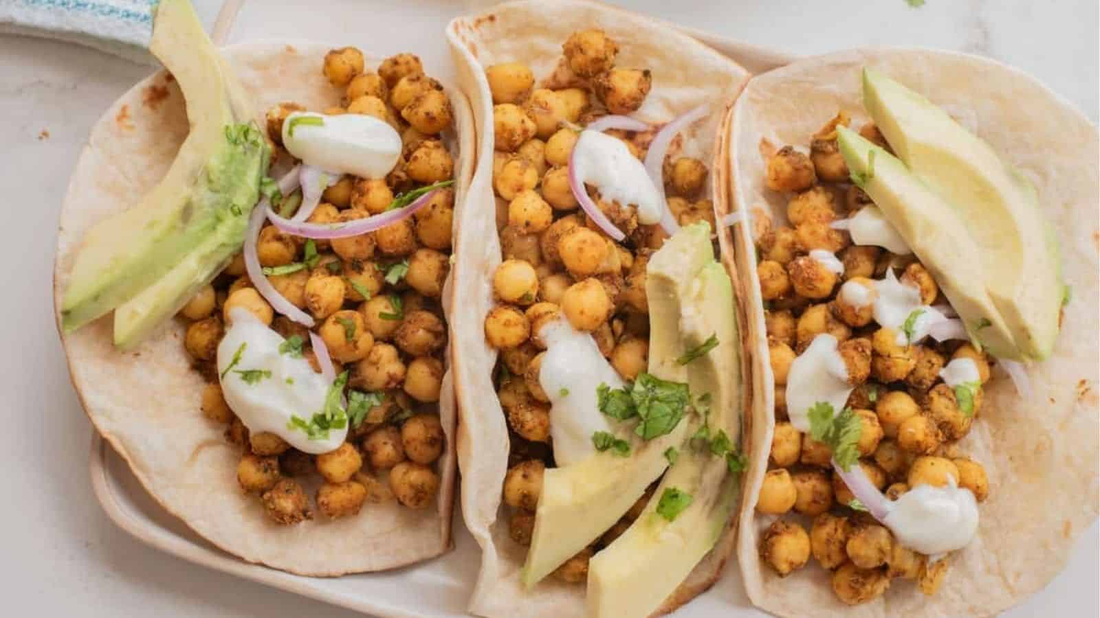 Overhead shot of three chickpea shawarma tacos on a white tray.