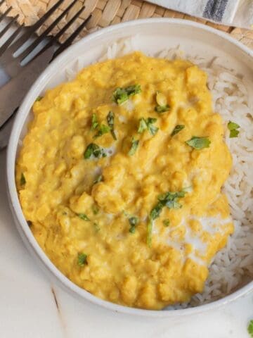 Coconut red lentil curry served in a bowl over white rice.
