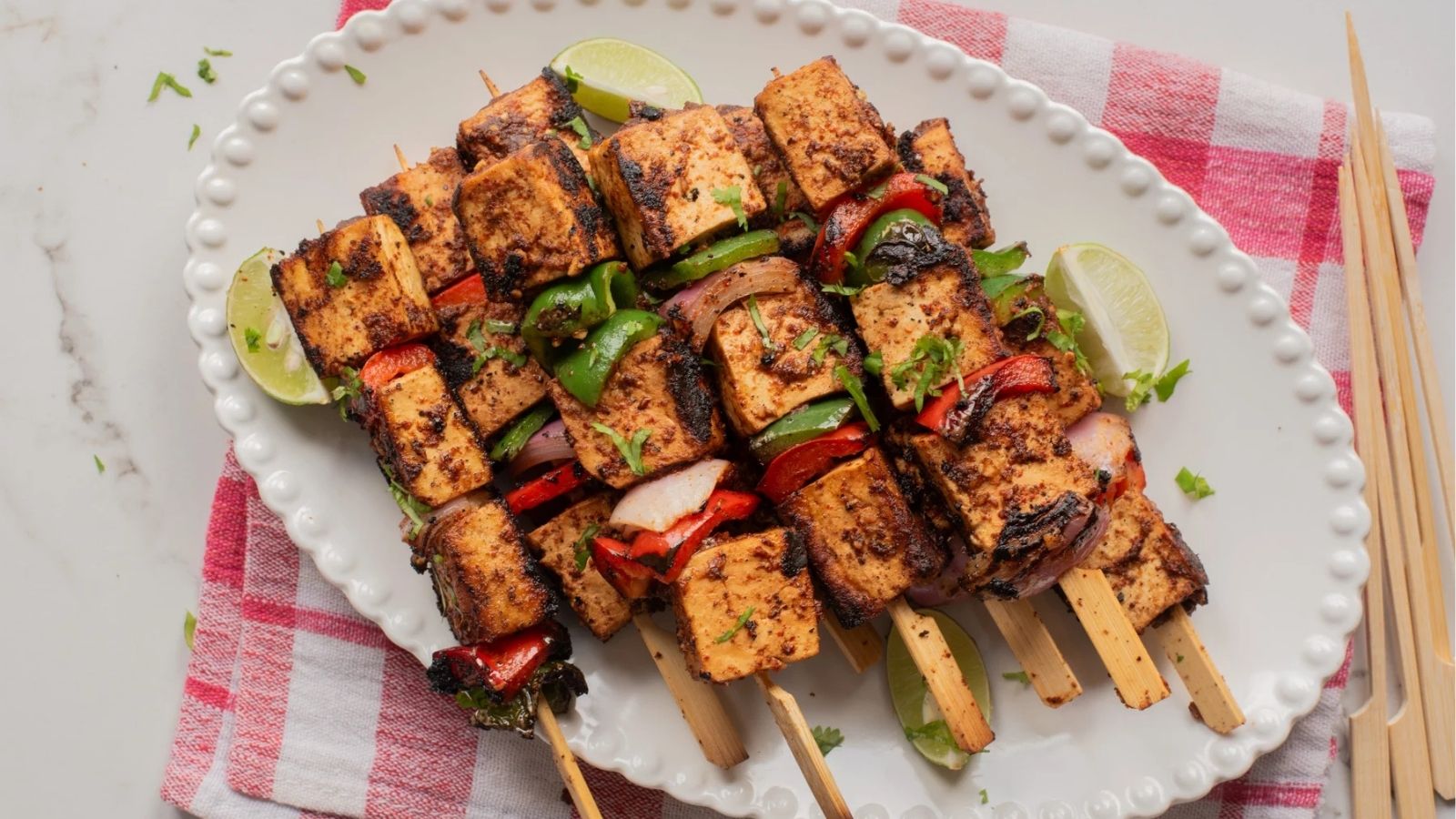 An overhead image of suya tofu skewers on a serving plate.