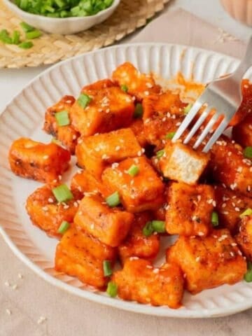 An image of a plate of buffalo tofu with a fork picking one up.