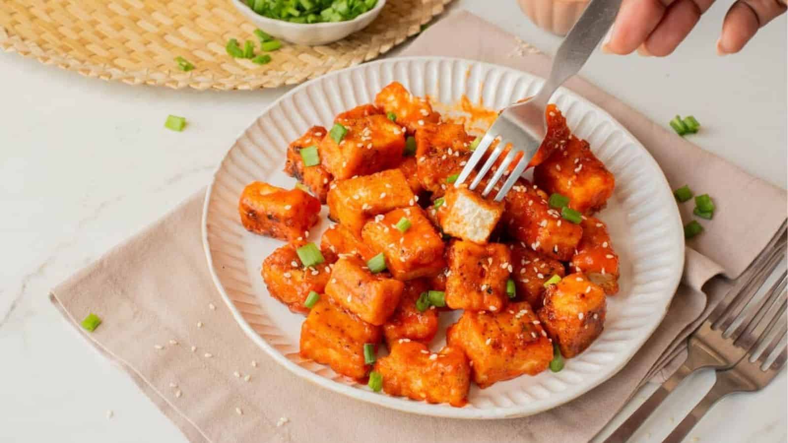An image of a plate of buffalo tofu with a fork picking one up.