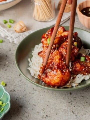 An image of Korean fried cauliflower in a plate with a person getting a piece.
