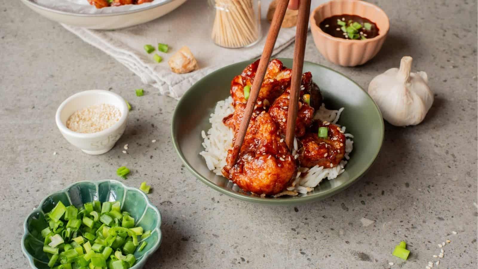 An image of Korean fried cauliflower in a plate with a person getting a piece.