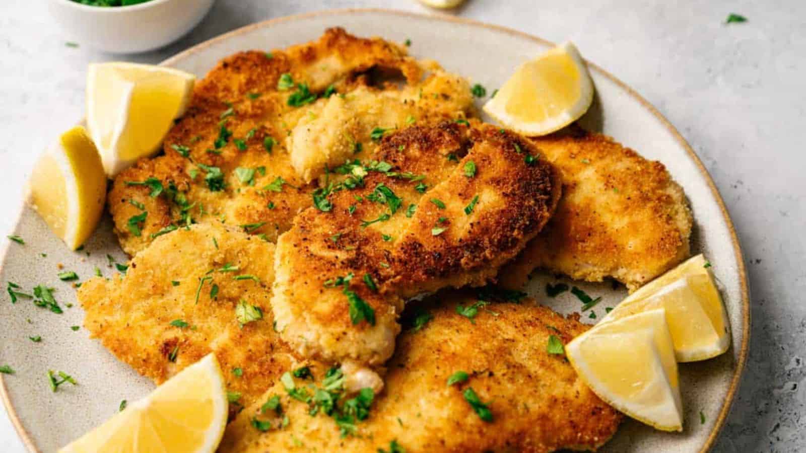 A plate of Chicken Cutlets with lemon slices.