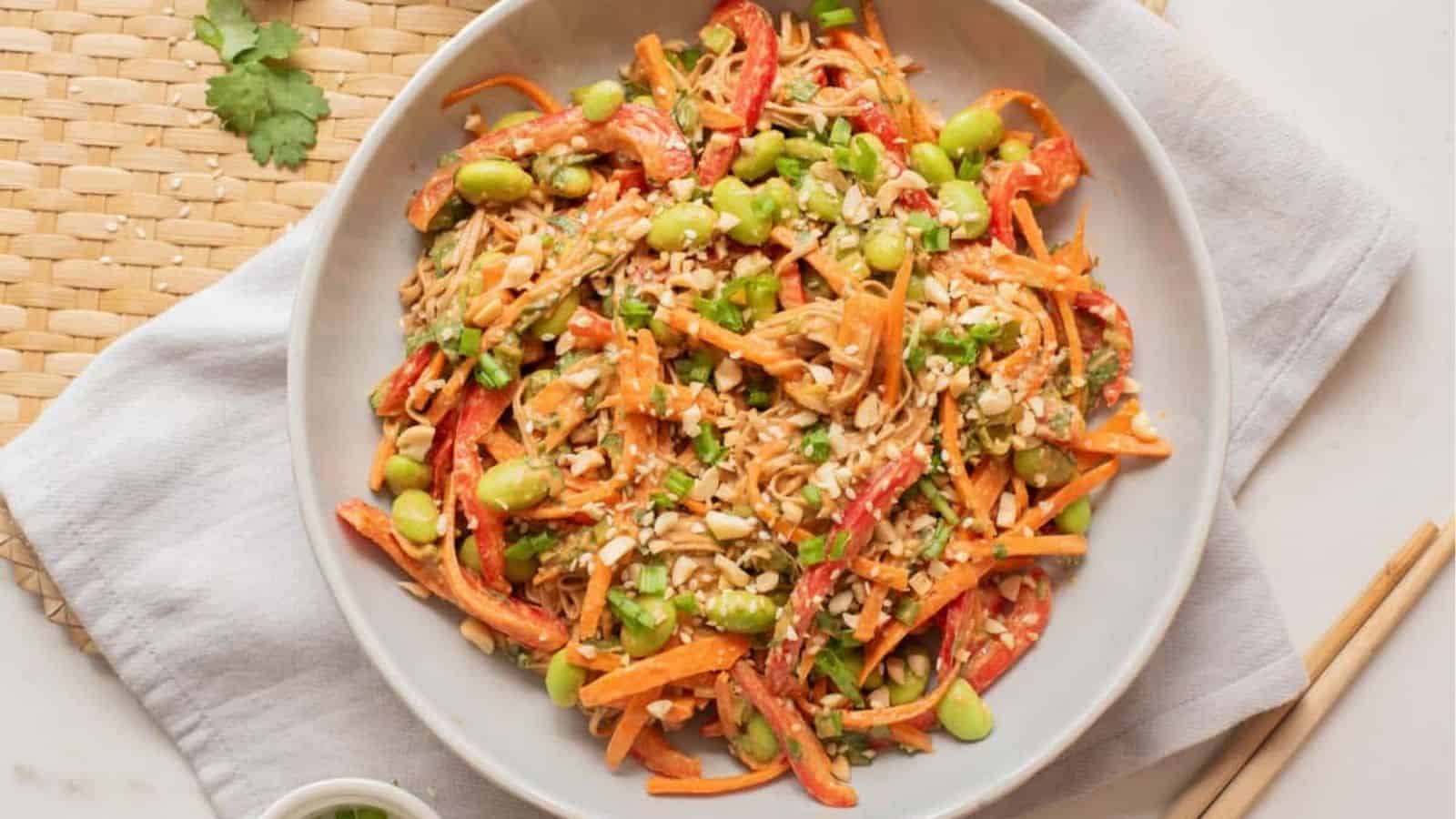 An overhead image of spicy peanut edamame noodles on a plate.