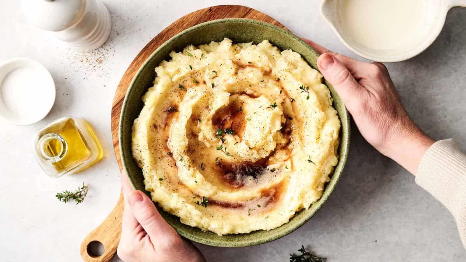 Someone holding a cowl of mashed potatoes.