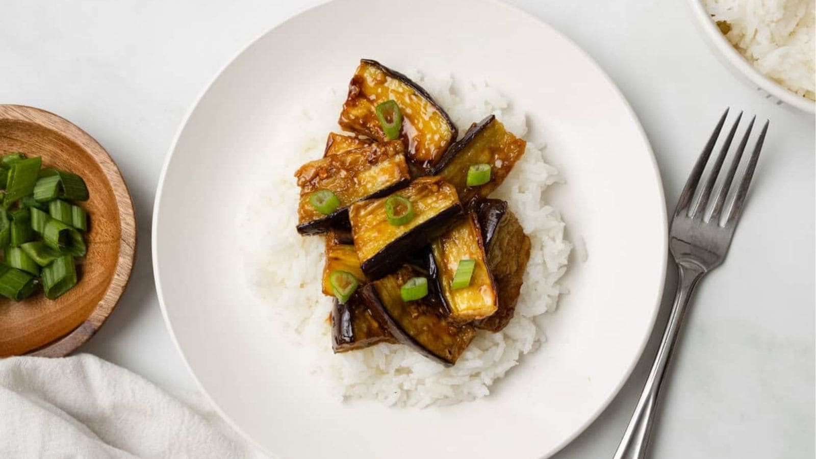 An overhead image of eggplant stir fry served over rice on a plate.