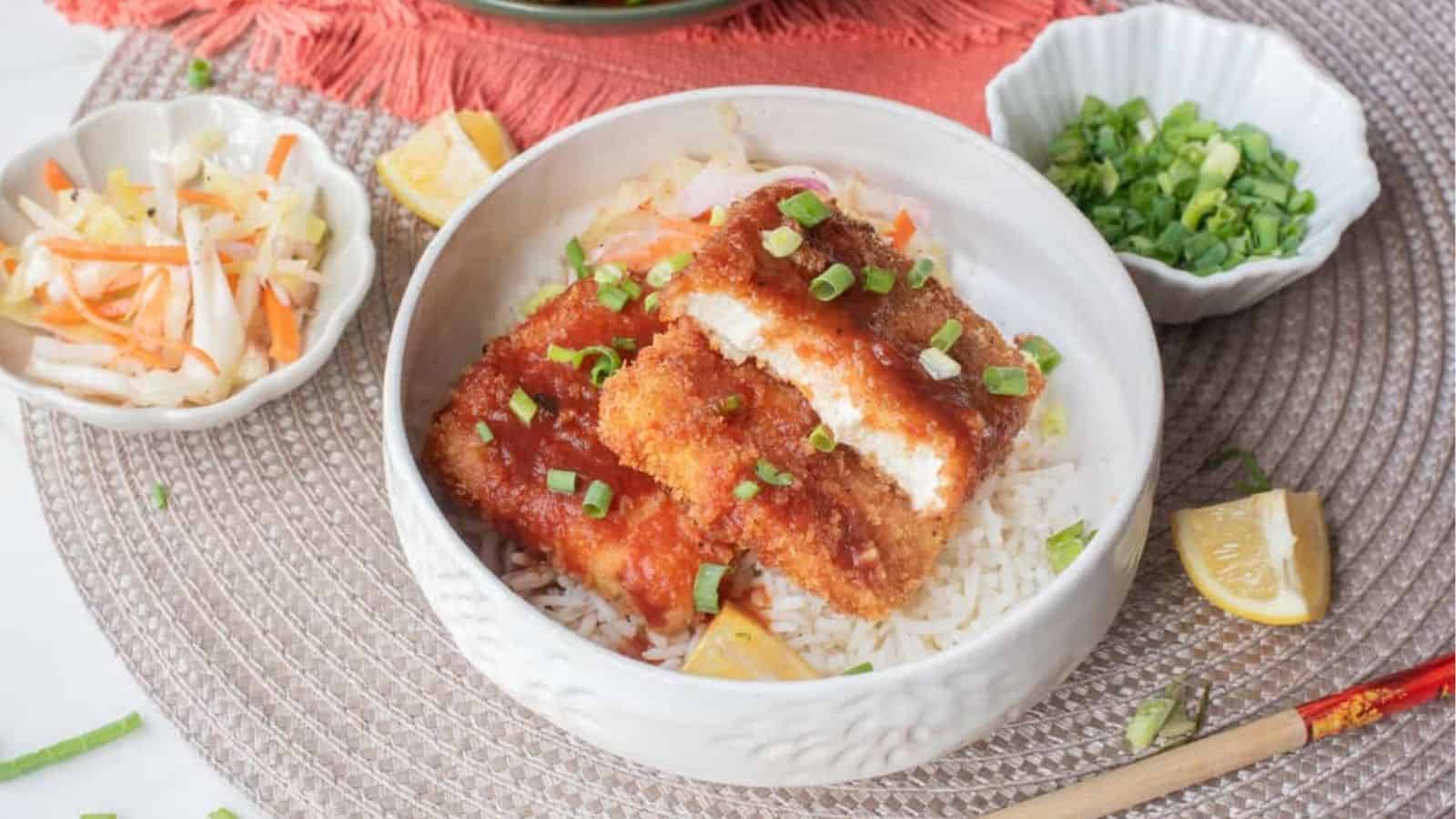 A close up image of tofu katsu served in a bowl over rice.