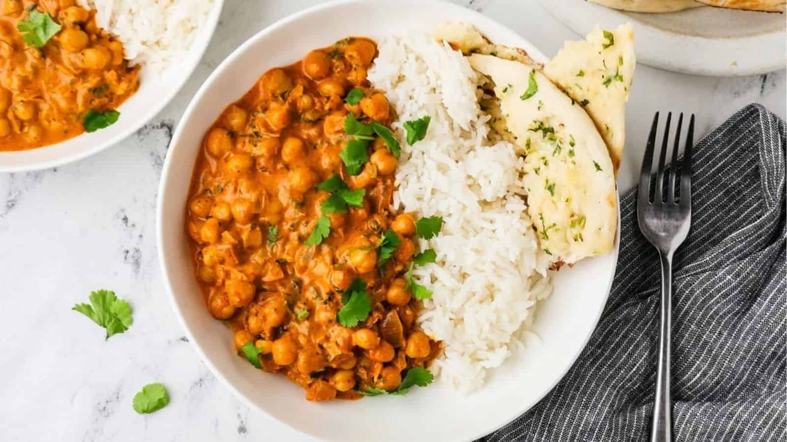 An overhead image of chickpea tikka masala served on a plate with rice and naan.