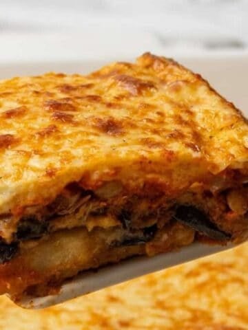 A close up image of a portion of vegetarian moussaka lifted up on a spatula.